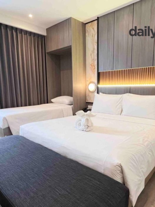 A modern hotel room featuring a Murphy bed (wall bed) that is partially folded or integrated into the wall to save space, showcasing a clean and functional interior design.